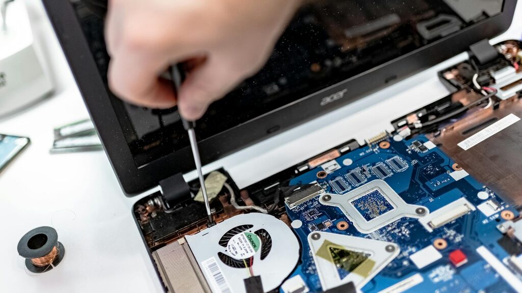 Hands working on a phone logic board with precision tools